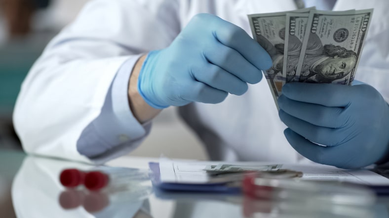 Doctor with gloves counting $100 bills