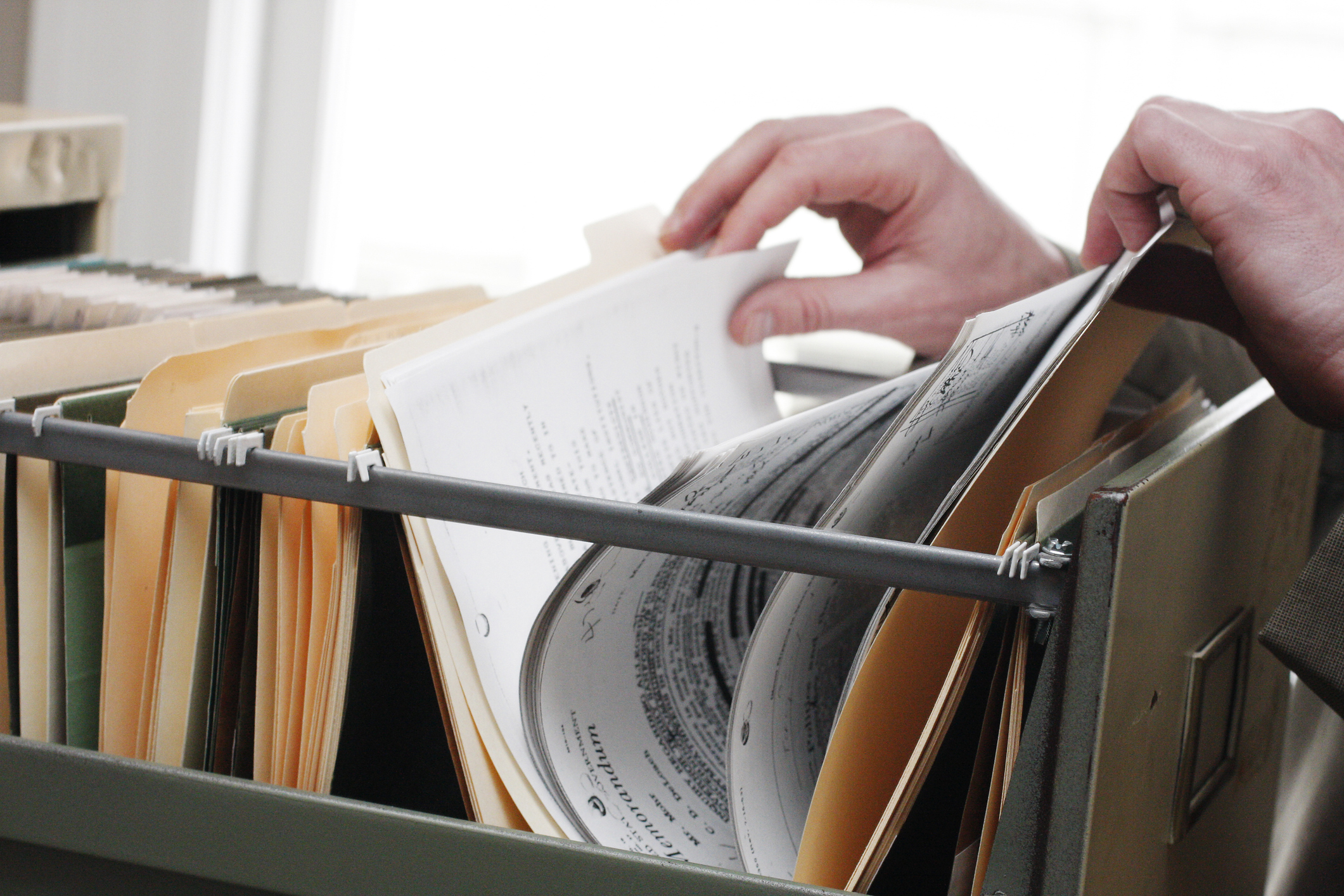 A person searching through a filing cabinet to make a false claims act lawsuit