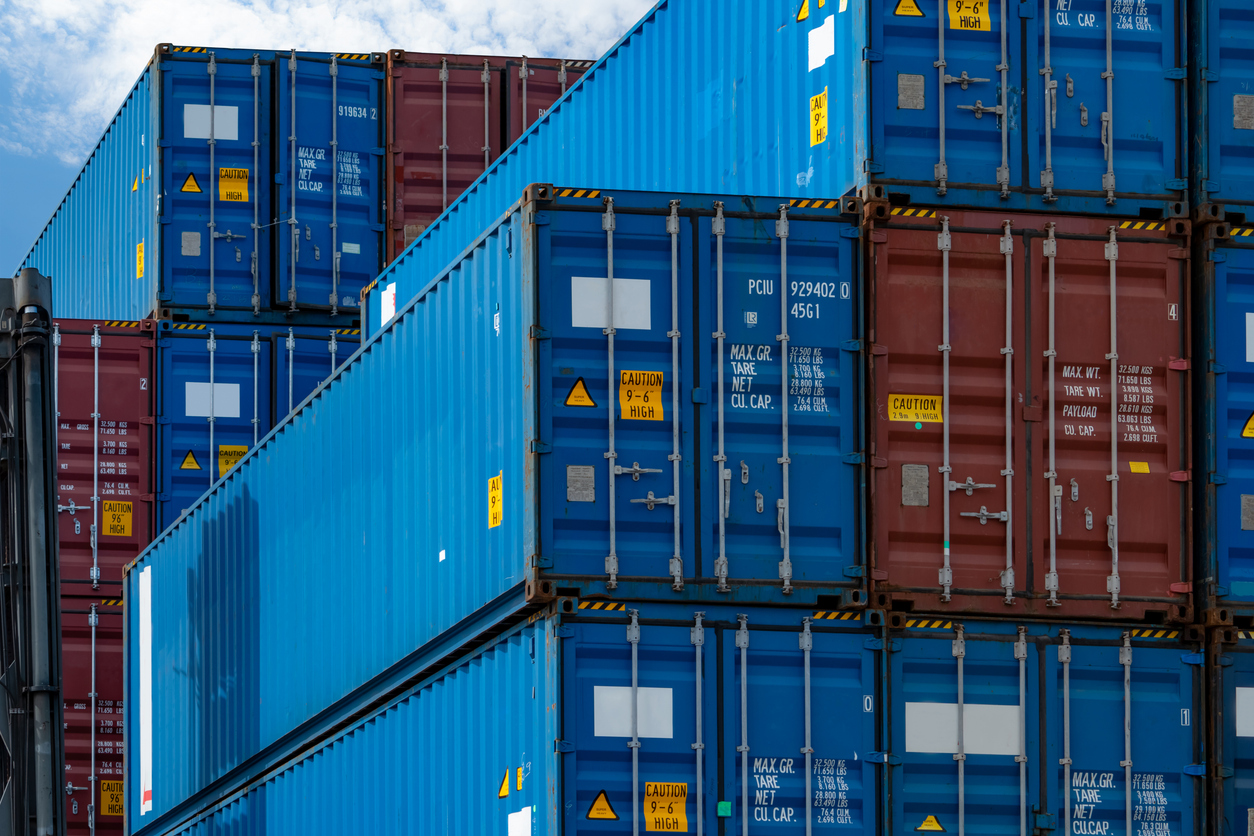 Close-up blue and red shipping containers stacked up at a port.